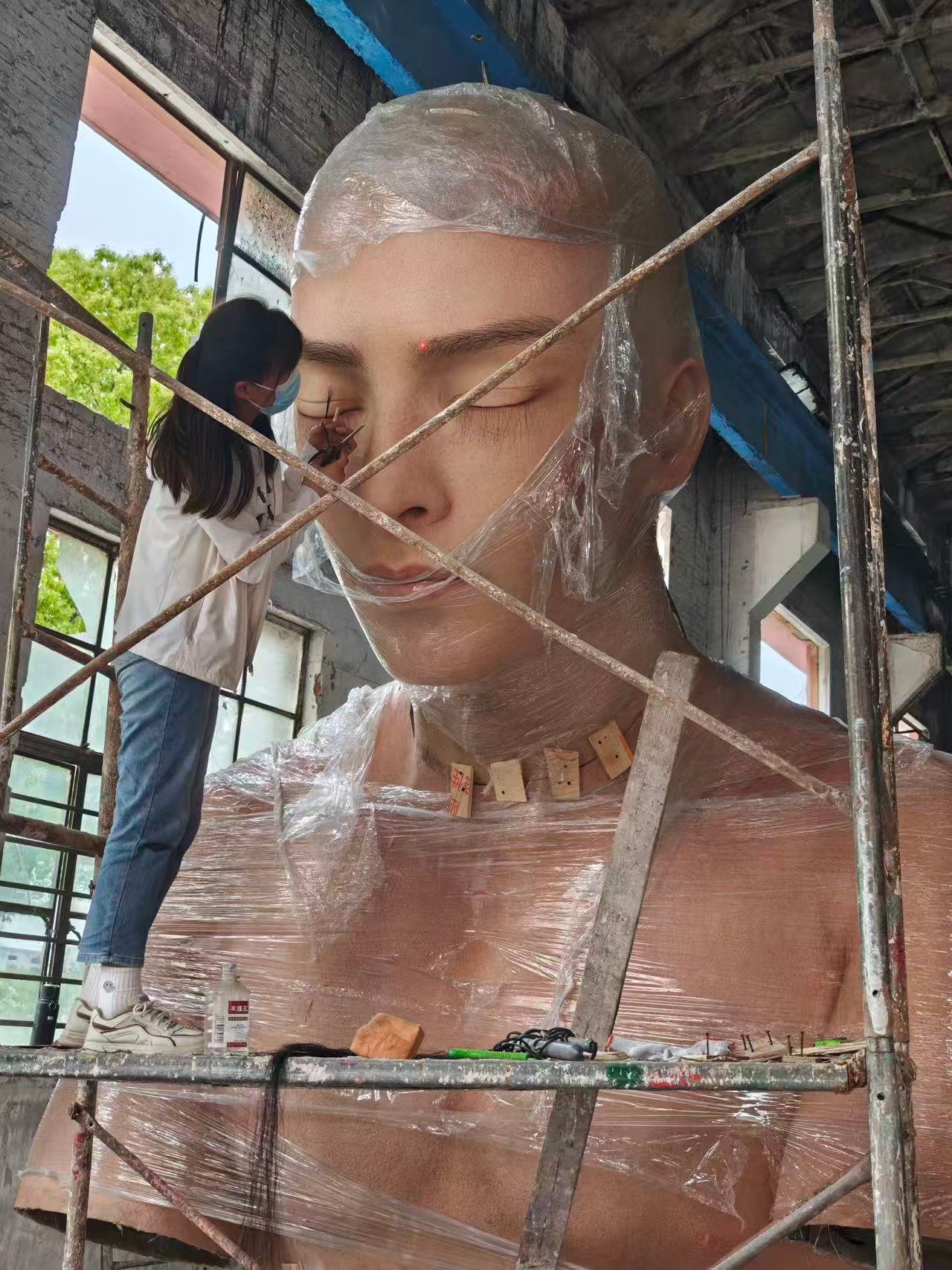 Close structural work on a monumental portrait head within scaffolding