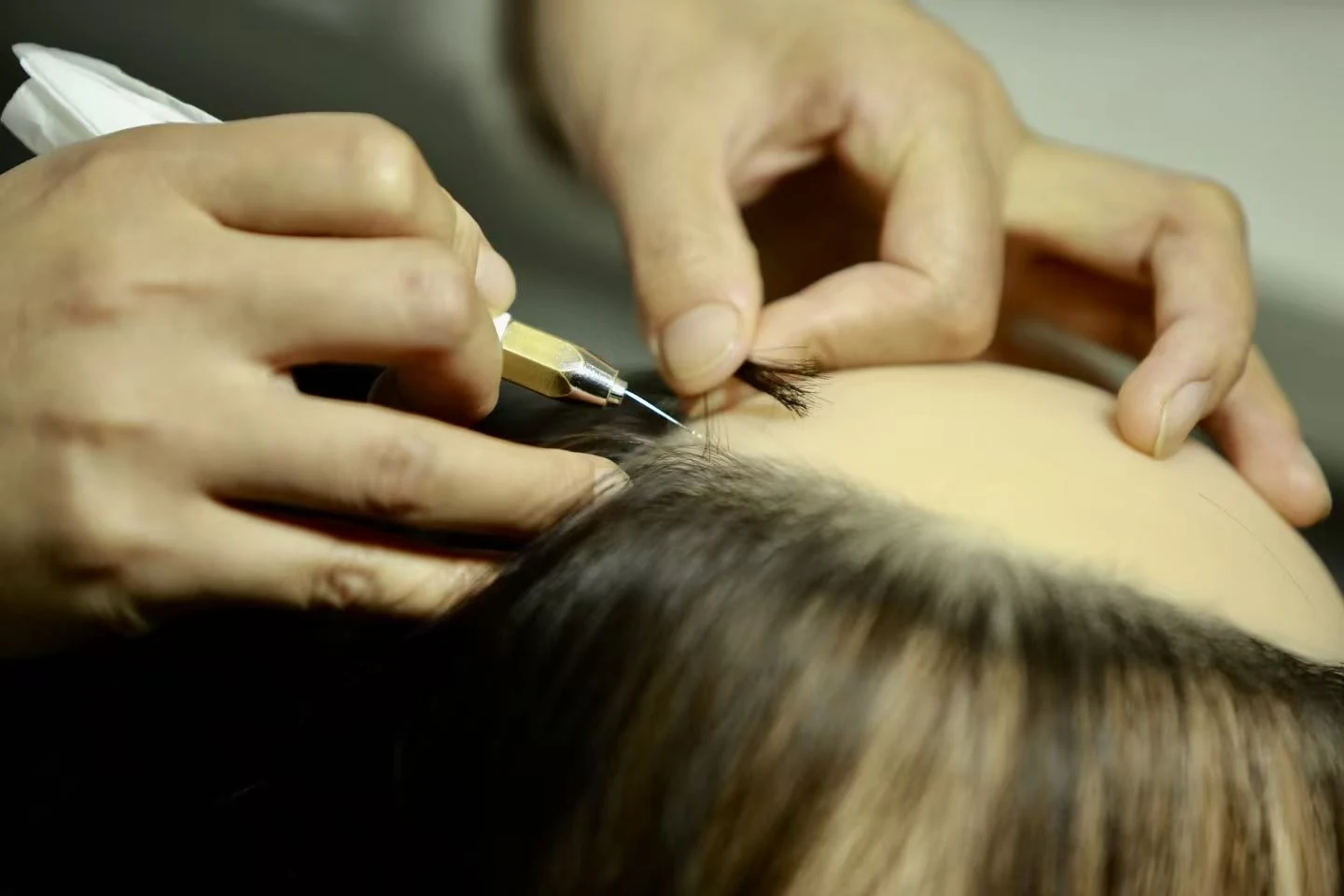 Individual hair being inserted by hand on a wax portrait