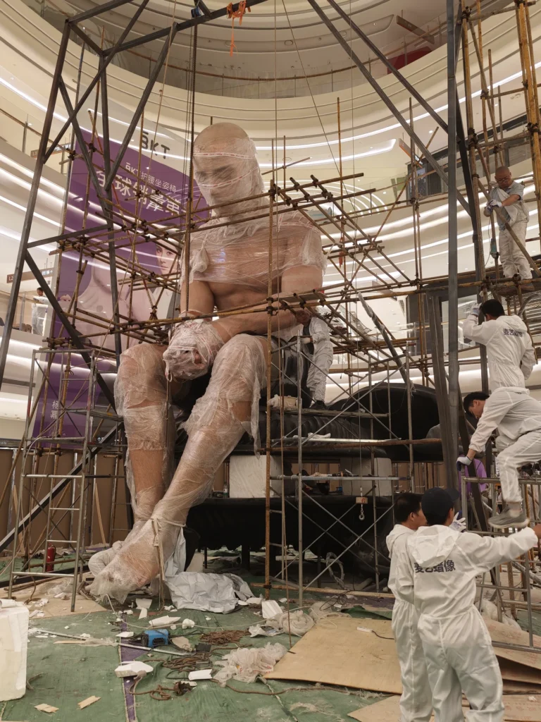 Installation of an eight-metre giant wax figure inside a shopping mall atrium.