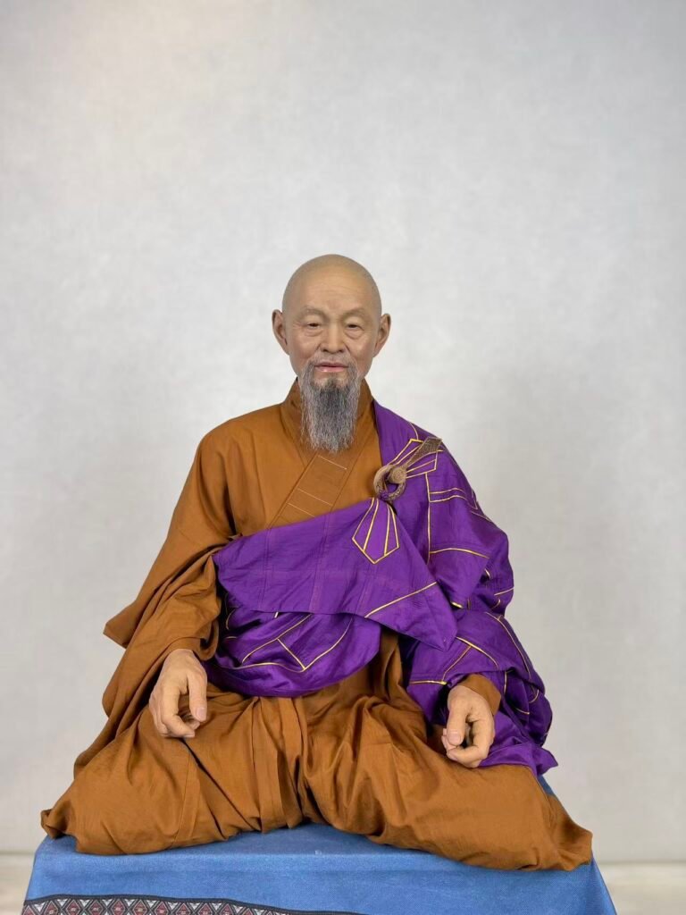 Handcrafted seated wax figure in brown and purple robes